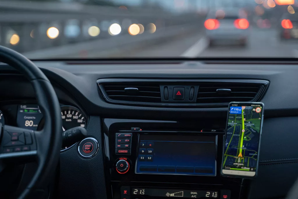 Dashboard of car with cell mounted with navigation displayed at night on freeway.